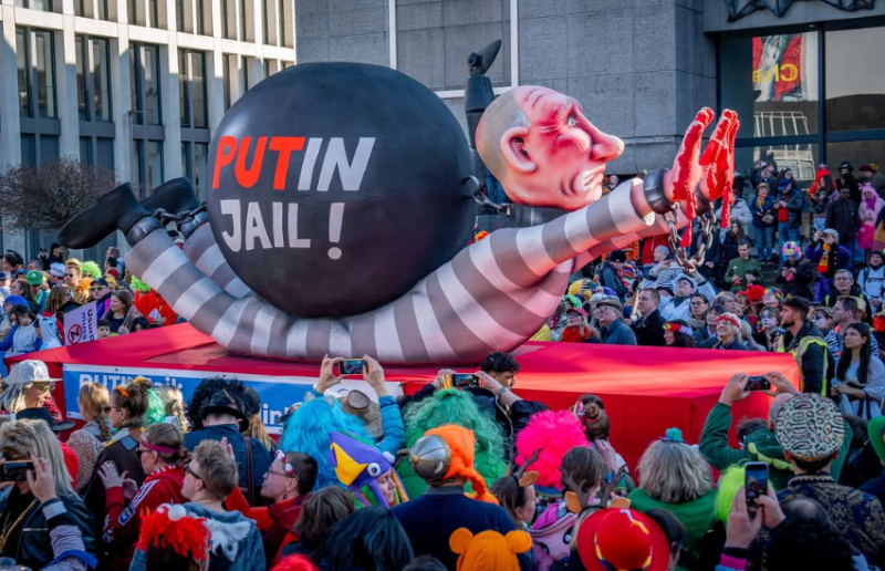 Dieser Wagen hat bereits eine weite Reise hinter sich: Er war im vergangenen Jahr anlässlich der fünften Amtseinführung Waldimir Putins schon in die Den Haag vor dem Internationalen Strafgerichtshof. Seit 2023 liegt ein internationaler Haftbefehl gegen den russischen Herrscher vor. Denn Putin gehört nicht auf den Präsidentenstuhl, er gehört in den Knast. Hier ist der Kreml-Chef in Sträflingskleidung und mit blutigen Händen dargestellt, gekettet an eine riesige Eisenkugel, auf der steht: "PUTin jail!" Wir stehen seit Jahren mit demokratischen Widerstandsorganisationen im Austausch, die häufig unsere Figuren über den Karneval hinaus einsetzen. Sei es im Kontext des Brexit, gegen die PiS-Partei in Polen oder eben für ein freiheitliches Russland. Foto: Ricarda Hinz